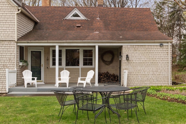 rear view of property featuring a shingled roof, a yard, and a chimney