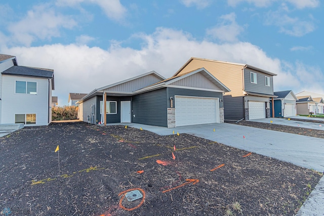 view of front of property featuring an attached garage, concrete driveway, and stone siding