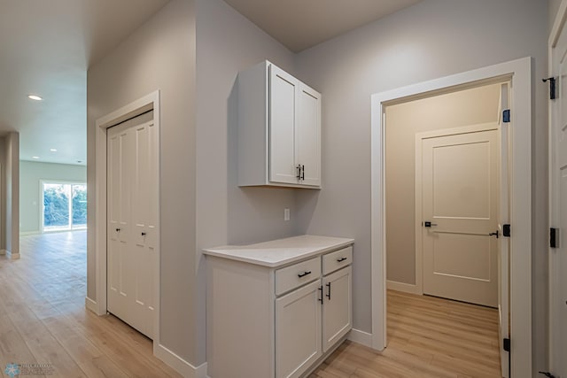 hallway with light wood-type flooring, recessed lighting, and baseboards