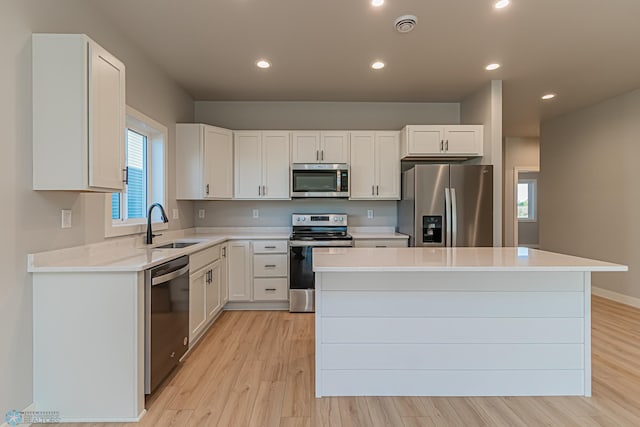 kitchen with a center island, light wood-style floors, stainless steel appliances, and a sink