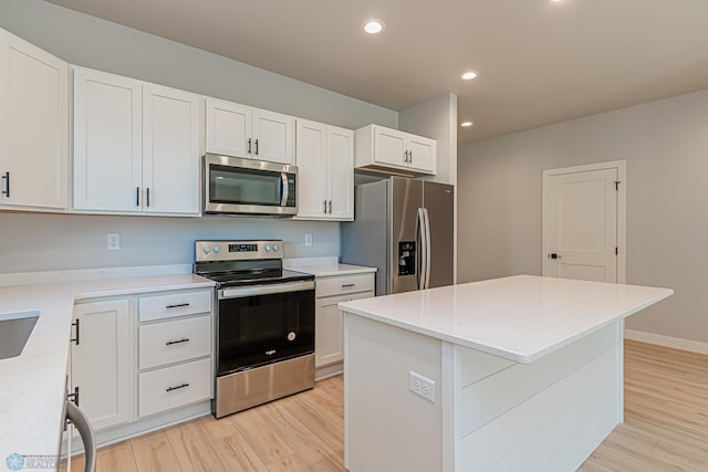 kitchen featuring white cabinets, light wood-type flooring, a center island, and appliances with stainless steel finishes