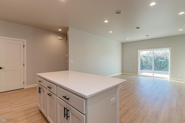 kitchen featuring recessed lighting, light wood-type flooring, a kitchen island, baseboards, and open floor plan