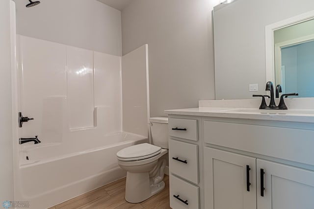 bathroom featuring toilet, vanity, shower / washtub combination, and wood finished floors