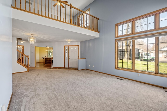 1904 Beebe Rd, Maplewood, MN 55109 - unfurnished living room featuring carpet flooring, stairs, baseboards, a towering ceiling, and healthy amount of natural light