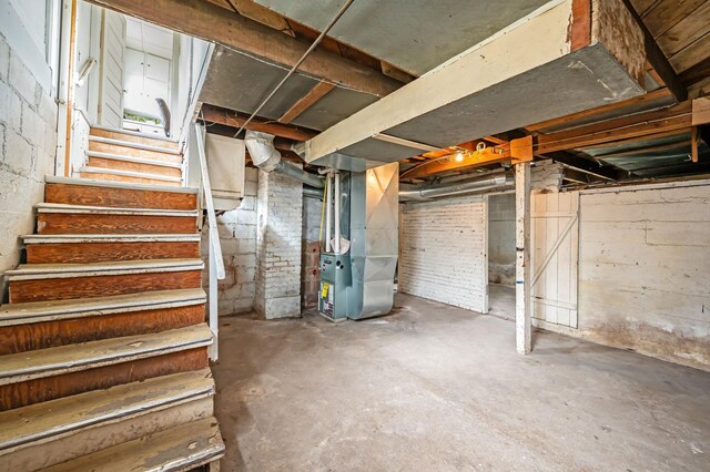 unfinished below grade area featuring heating unit and stairs
