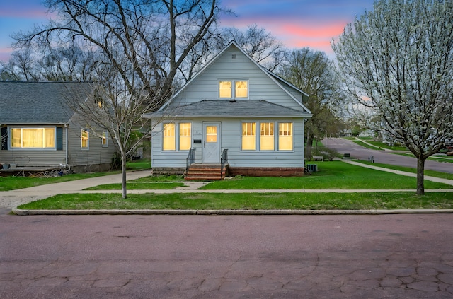 bungalow-style house featuring a shingled roof and a front yard