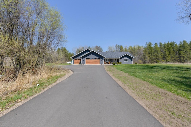 ranch-style house with a front lawn, an attached garage, and asphalt driveway