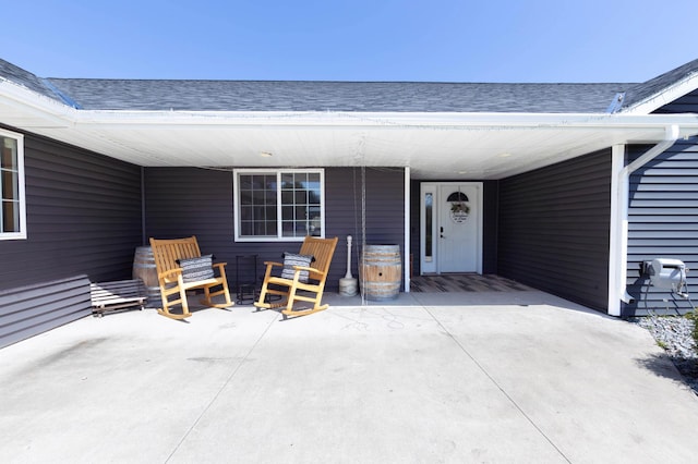 doorway to property featuring roof with shingles and a carport