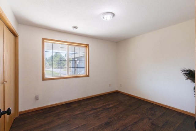 unfurnished room with dark wood-style flooring and baseboards