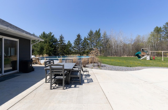 view of patio / terrace featuring a playground, outdoor dining area, and an outdoor pool