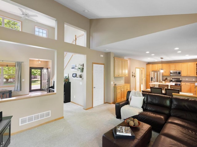 living area featuring baseboards, light colored carpet, ceiling fan, a high ceiling, and recessed lighting