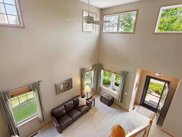 living area with a towering ceiling, a ceiling fan, and light tile patterned floors