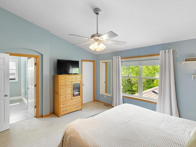 bedroom featuring multiple windows, light carpet, baseboards, ceiling fan, and vaulted ceiling