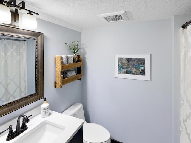 bathroom featuring a textured ceiling, toilet, and vanity