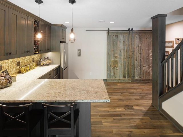 kitchen featuring freestanding refrigerator, dark wood-style flooring, tasteful backsplash, dark brown cabinetry, and a peninsula
