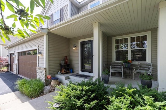 entrance to property with asphalt driveway, covered porch, and a garage