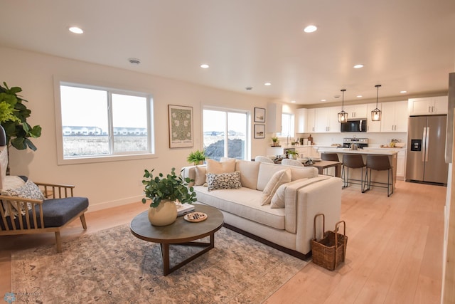 living room featuring baseboards, light wood finished floors, and recessed lighting