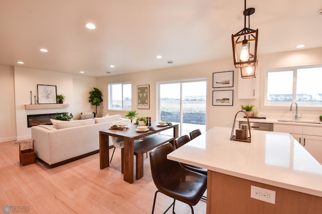 interior space featuring recessed lighting, a glass covered fireplace, and light wood-type flooring