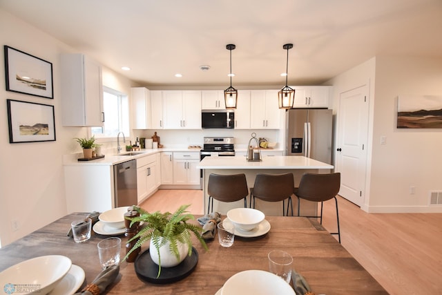 kitchen featuring visible vents, appliances with stainless steel finishes, a sink, light countertops, and light wood-style flooring