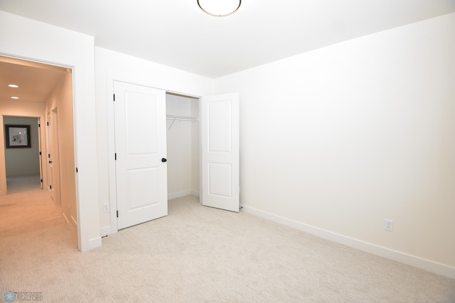 unfurnished bedroom featuring recessed lighting, baseboards, light colored carpet, and a closet