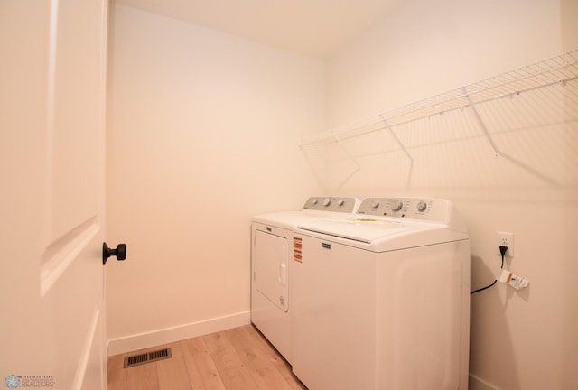 clothes washing area featuring laundry area, light wood finished floors, separate washer and dryer, baseboards, and visible vents
