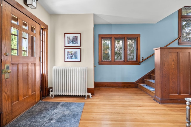 foyer entrance with stairs, light wood finished floors, a wealth of natural light, and radiator