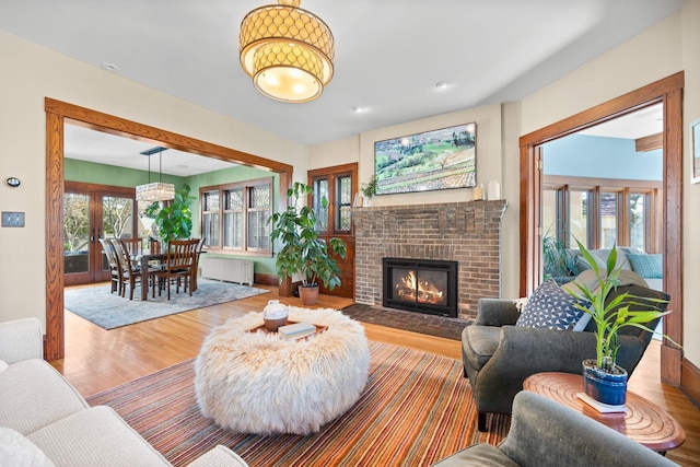 living area with a brick fireplace, wood finished floors, and radiator