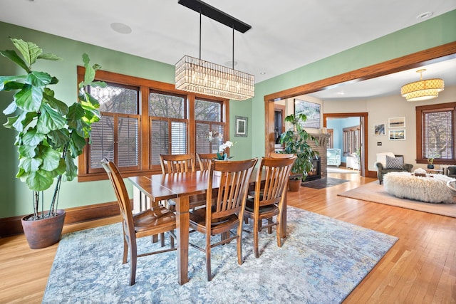 dining space featuring a brick fireplace, wood finished floors, and a chandelier
