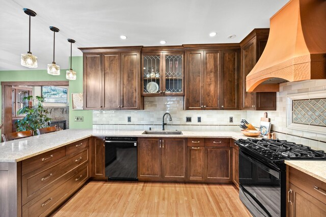 kitchen featuring a sink, premium range hood, a peninsula, light wood-type flooring, and black appliances