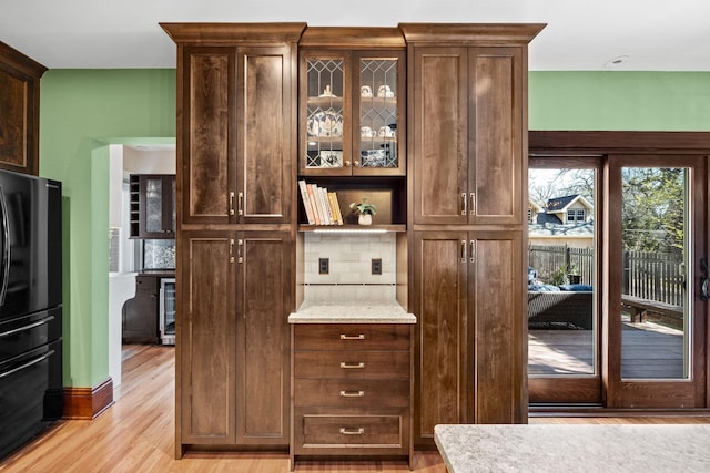 interior space featuring light wood-type flooring, freestanding refrigerator, decorative backsplash, and beverage cooler