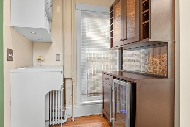 bar with beverage cooler, baseboards, a wealth of natural light, and light wood-style flooring