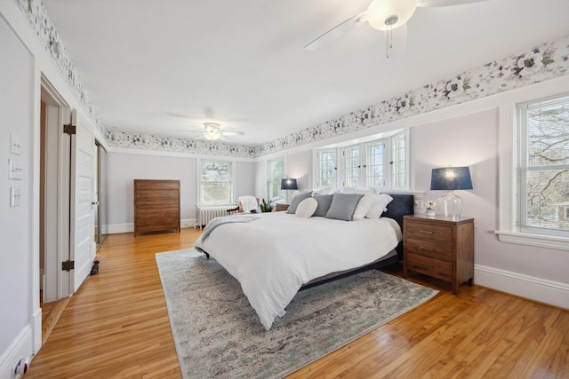 bedroom featuring radiator heating unit, baseboards, multiple windows, and light wood-style floors