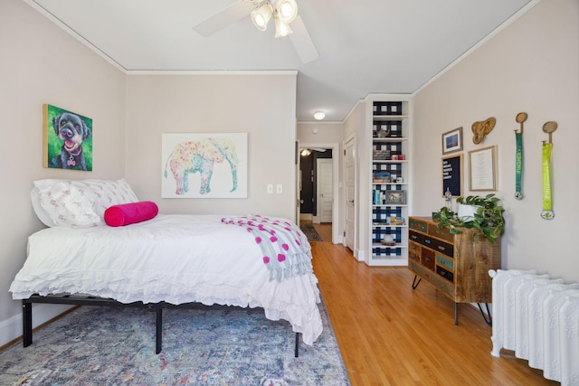 bedroom featuring crown molding, a ceiling fan, radiator, and wood finished floors