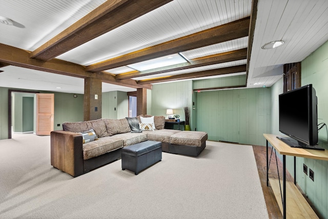 carpeted living area with wood walls and beam ceiling
