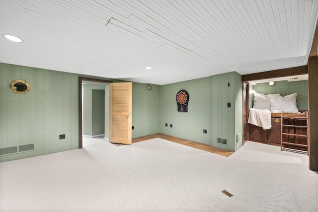 carpeted spare room featuring visible vents, wood walls, and wood ceiling