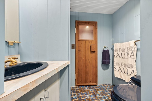 half bath with vanity and wooden walls