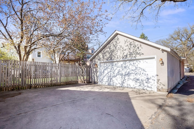 garage with fence and concrete driveway