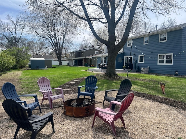view of yard featuring a storage unit, a fire pit, and an outbuilding