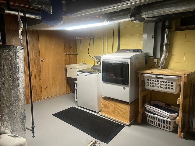 washroom featuring laundry area, a sink, separate washer and dryer, and concrete block wall