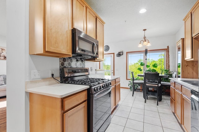 15601 Lilac Dr, Eden Prairie, MN 55347 - kitchen with appliances with stainless steel finishes, light countertops, a chandelier, backsplash, and hanging light fixtures