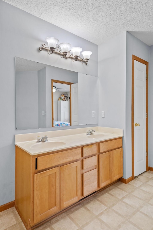 15601 Lilac Dr, Eden Prairie, MN 55347 - bathroom with double vanity, baseboards, a textured ceiling, and a ceiling fan