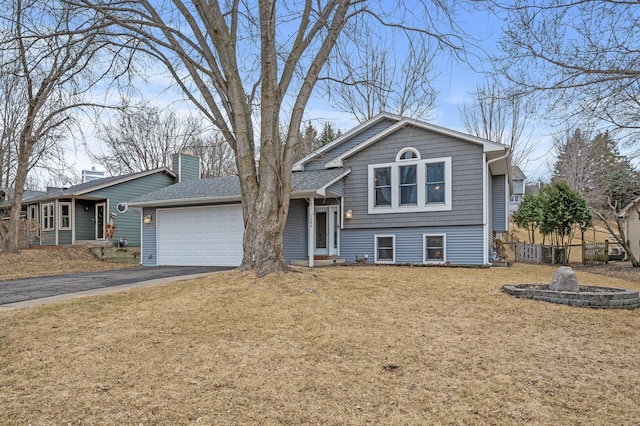 tri-level home featuring a garage, fence, aphalt driveway, and a front yard