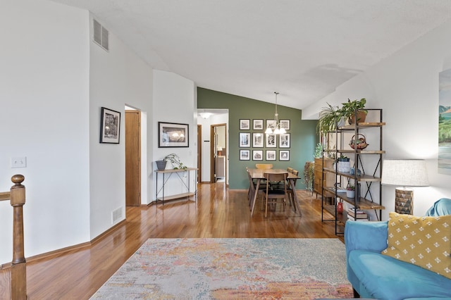 living room with visible vents, a chandelier, wood finished floors, and lofted ceiling