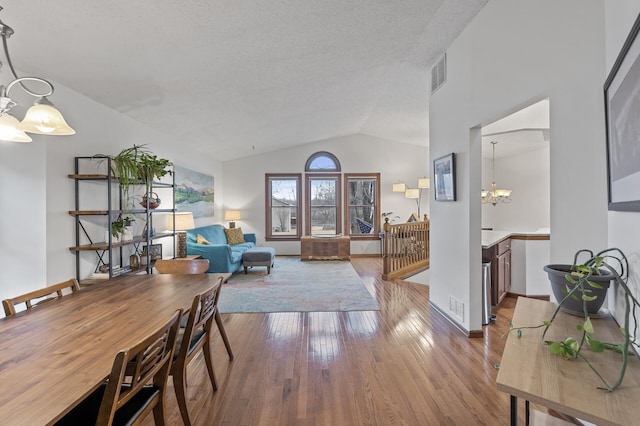 living room featuring a chandelier, visible vents, hardwood / wood-style flooring, and vaulted ceiling