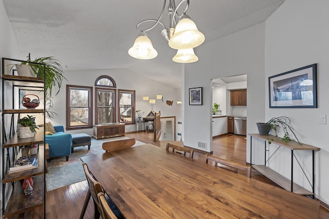 dining area featuring visible vents, hardwood / wood-style flooring, an inviting chandelier, and lofted ceiling