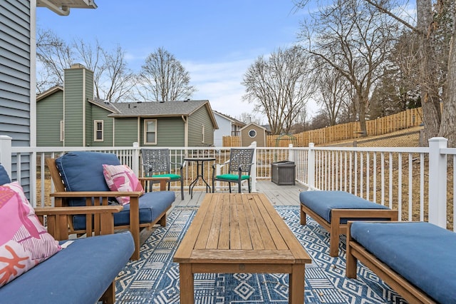 view of patio featuring fence, an outdoor structure, a wooden deck, and a storage shed