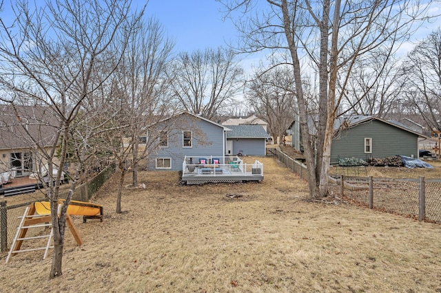rear view of house featuring a wooden deck, roof with shingles, and fence