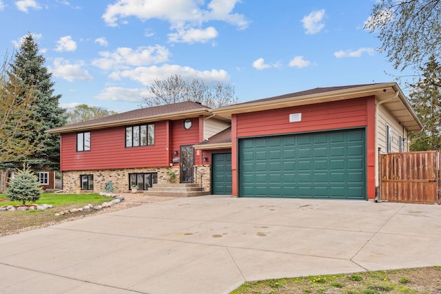 split level home featuring an attached garage, fence, and concrete driveway