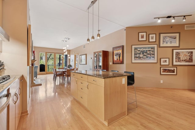 401 2nd St Unit 202, Minneapolis, MN 55401 - kitchen with light wood finished floors, a breakfast bar, light brown cabinetry, visible vents, and a kitchen island