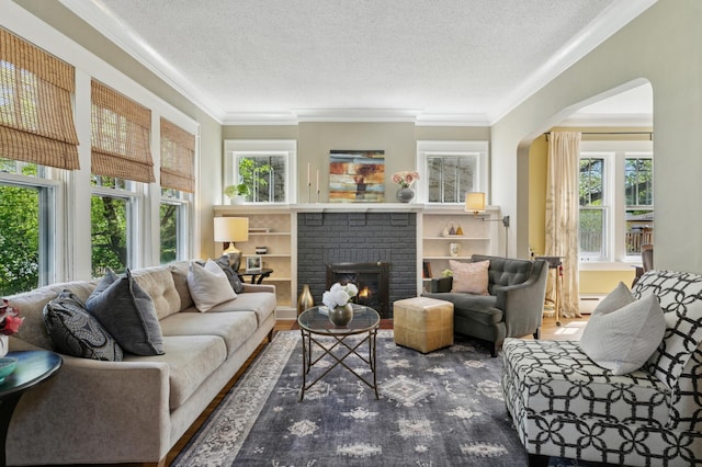 living area featuring ornamental molding, a textured ceiling, a fireplace, arched walkways, and wood finished floors